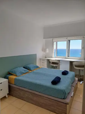 a bedroom with a bed and a desk and windows at Appartement vista Mar Quarteira in Quarteira