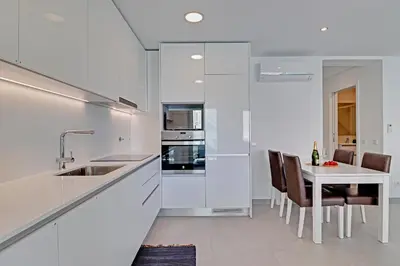 a kitchen with white cabinets and a table with chairs at Ocean Chic by the Beach in Albufeira