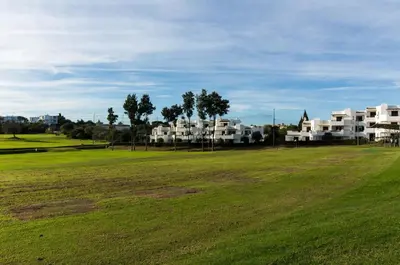 a green field with white apartment complexes in the background at Apartamento Luna - Golf View By Dalma Portuguesa in Albufeira