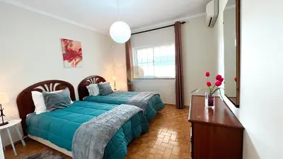 a bedroom with two beds and a table with flowers at Villa Gilsónia by Sunny Deluxe in Guia