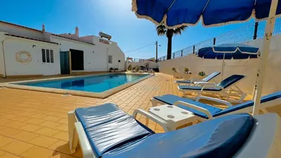 a swimming pool with lounge chairs and an umbrella at Villa Gilsónia by Sunny Deluxe in Guia