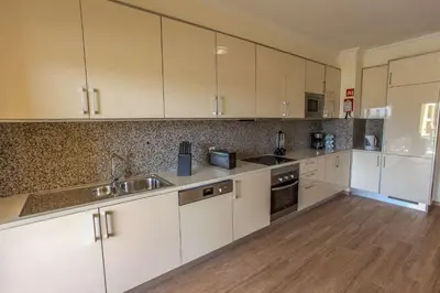 a large kitchen with white cabinets and a wooden floor at Apartment Aria - Great area for children in Albufeira