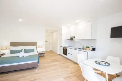 a bedroom with a bed and a kitchen with a table at Studio Pimenta - Short walk to the beach in Albufeira