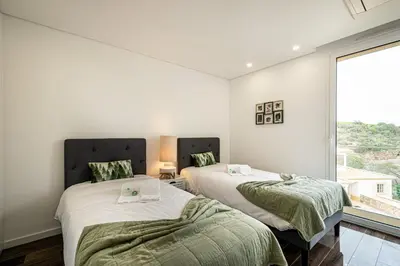 two beds in a room with a large window at BeGuest Albufeira Luxus Villa in Albufeira
