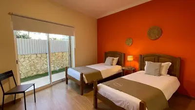 two beds in a room with orange walls and a window at Oura Oasis C by Check-in Portugal in Albufeira