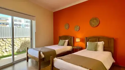 two beds in a room with an orange wall at Oura Oasis C by Check-in Portugal in Albufeira