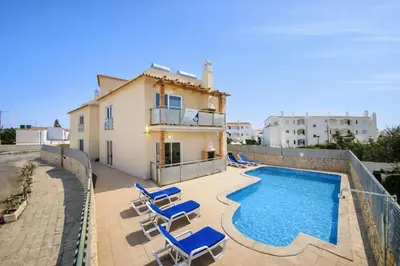 a villa with a swimming pool and some blue chairs at Oura Oasis D by Check-in Portugal in Albufeira