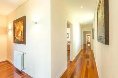 a hallway with white walls and wooden floors and paintings at Villa Atlantic Pearl - Luxury villa located in in Quinta do Lago