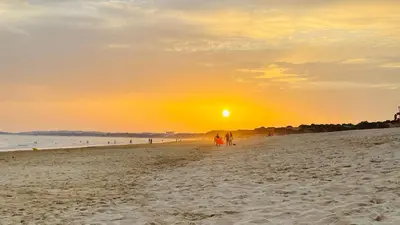 a group of people walking on the beach at sunset at Moon by Check-in Portugal in Albufeira