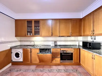 a kitchen with wooden cabinets and a sink at Vilamoura Paradise Golf With Pool by Homing in Vilamoura