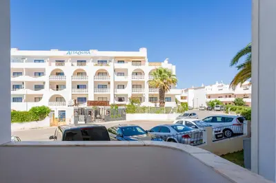 a large white building with cars parked in a parking lot at Duas Palmeiras by LovelyStay in Albufeira