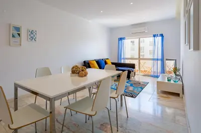 a dining room and living room with a table and chairs at Duas Palmeiras by LovelyStay in Albufeira