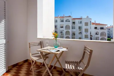 a small table and chairs on a balcony with a window at Duas Palmeiras by LovelyStay in Albufeira