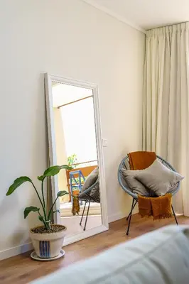a mirror in a bedroom with a chair and a plant at Estúdio do Largo - Vilamoura in Vilamoura