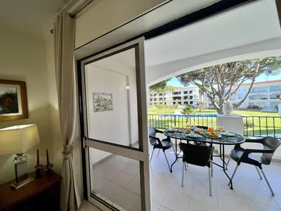 a dining room with a table and chairs and a glass door at Vilamoura Garden View 1 With Pool by Homing in Vilamoura