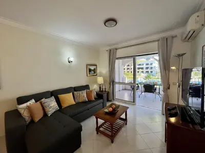 a living room with a black couch and a table at Vilamoura Garden View 1 With Pool by Homing in Vilamoura