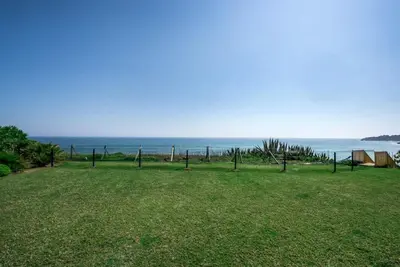 a field of grass with the ocean in the background at Villa Plage Grande - Superstar luxury - Beachtop in Olhos de Água