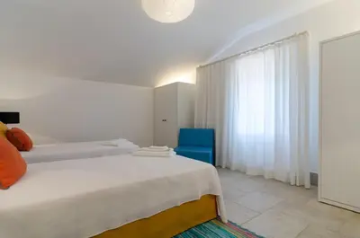 a white bedroom with two beds and a blue chair at Villa Colom in Quarteira