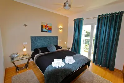 a bedroom with a large bed with blue curtains at Spacious Vilamoura Villa 4 Bedrooms Villa Amendoeira Table Tennis in Quarteira