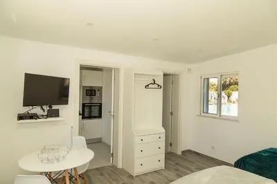 a white room with a bed and a table and a tv at O Pinhal do Avô - BY BEDZY in Almancil