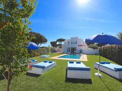 a yard with couches and umbrellas and a pool at Superb Vilamoura Villa 5 Bedrooms Villa Azul Walking Distance To Marina in Quarteira