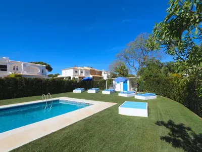 a yard with a swimming pool with chairs and a house at Superb Vilamoura Villa 5 Bedrooms Villa Azul Walking Distance To Marina in Quarteira