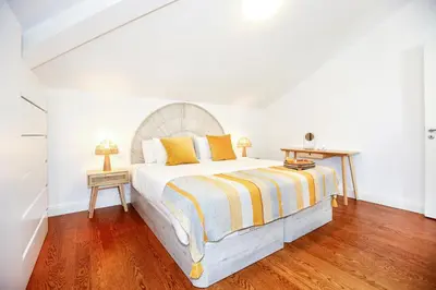 a bedroom with a large bed with a wooden floor at Tropical Flavour Apartment in Faro