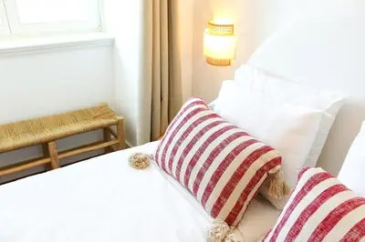 a white bed with two striped pillows on it at Tropical Flavour Apartment in Faro