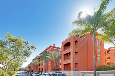 an orange building with palm trees in front of it at Victoria Garden in Vilamoura