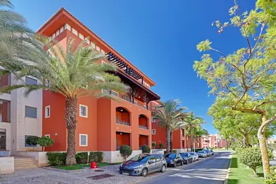 a red building with cars parked in front of it at Victoria Garden in Vilamoura