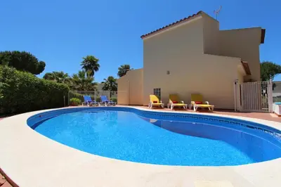 a swimming pool with chairs and a house at Modern Vilamoura Villa Close To Pinhal Golf Villa Maelou 4 Bedrooms in Quarteira