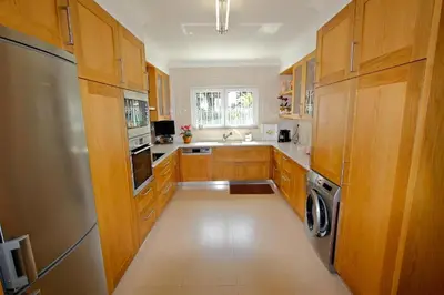 a kitchen with wooden cabinets and a stainless steel refrigerator at Contemporary Portuguese Villa 4 Bedrooms Villa Violeta Private Pool in Quarteira