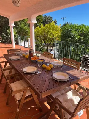 a wooden table with plates and glasses on a patio at Beautiful private Villa with pool, Boliqueime, Loulé in Boliqueime