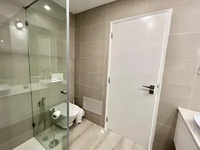 a bathroom with a toilet and a glass shower door at Oceanview - Sea front by HD PROPERTIES in Quarteira