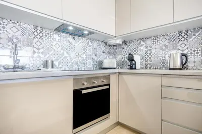 a kitchen with white cabinets and a black oven at Albufeira Holidays Near The Strip in Albufeira