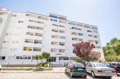 a white building with cars parked in front of it at Albufeira Holidays Near The Strip in Albufeira