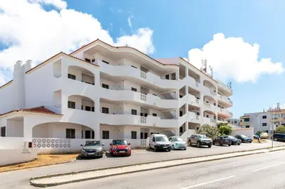a large white building with cars parked in a parking lot at Apart 306 in Albufeira