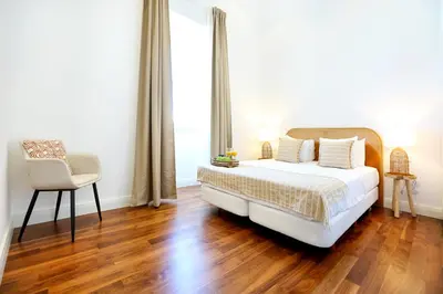 a bedroom with a bed and a chair and a window at Zen & Tan Apartment in Faro
