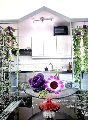 a glass bowl with purple flowers on a kitchen counter at Albufeira SPOT com piscinas exteriores e interior! in Albufeira