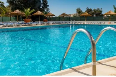 a swimming pool with chairs and an umbrella at Albufeira SPOT com piscinas exteriores e interior! in Albufeira