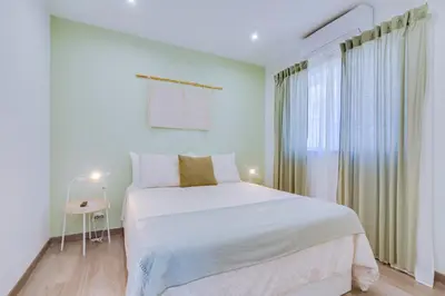 a white bedroom with a bed and a window at Faro: Casa Trevo com terraço BBQ in Faro