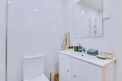 a white bathroom with a sink and a mirror at Faro: Casa Trevo com terraço BBQ in Faro