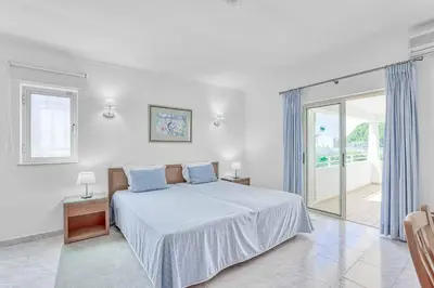 a white bedroom with a bed with blue pillows at Isabel Vivenda in Patroves