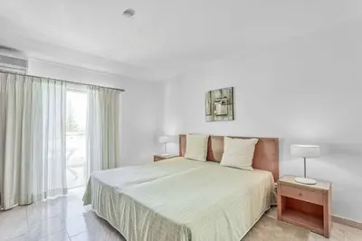 a white bedroom with a bed and a window at Isabel Vivenda in Patroves