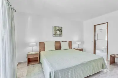a white bedroom with a bed and a mirror at Isabel Vivenda in Patroves