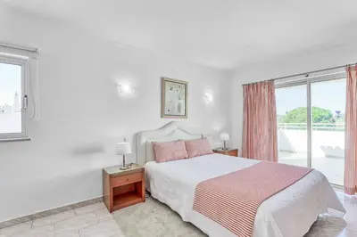 a white bedroom with a bed and a window at Isabel Vivenda in Patroves