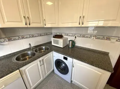 a kitchen with white cabinets and a sink at Apartamento Mimosas in Albufeira