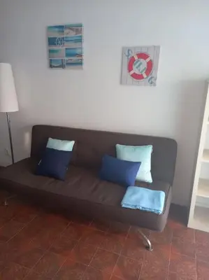 a brown couch with blue pillows in a room at Apartamento em Quarteira in Quarteira