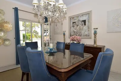 a dining room with a glass table and blue chairs at Villa Casa Tulipa Sleeps 4 with Pool Garden & A c in Albufeira