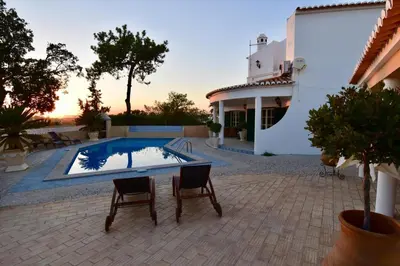 a patio with a pool and two chairs and a house at Villa Casa Tulipa Sleeps 4 with Pool Garden & A c in Albufeira